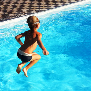 boy jumping into swimming pool